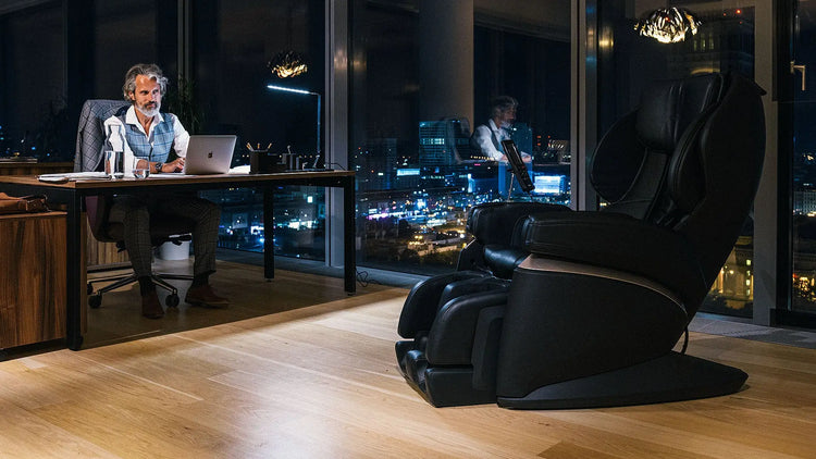 Moderne kantoortafel met persoon die aan laptop werkt in collectie massagestoelen.