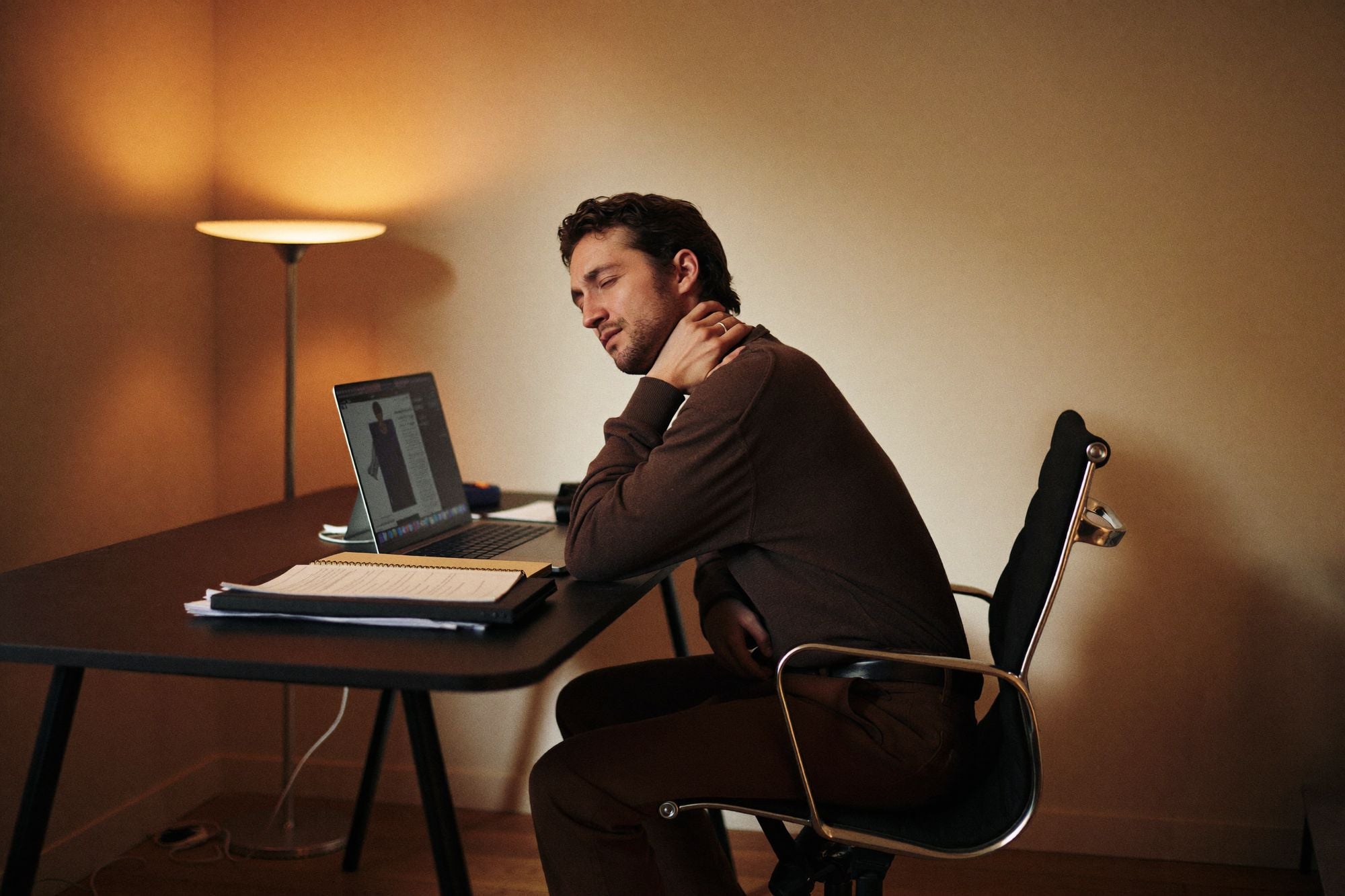 Man aan zijn bureau houdt zijn nek vast