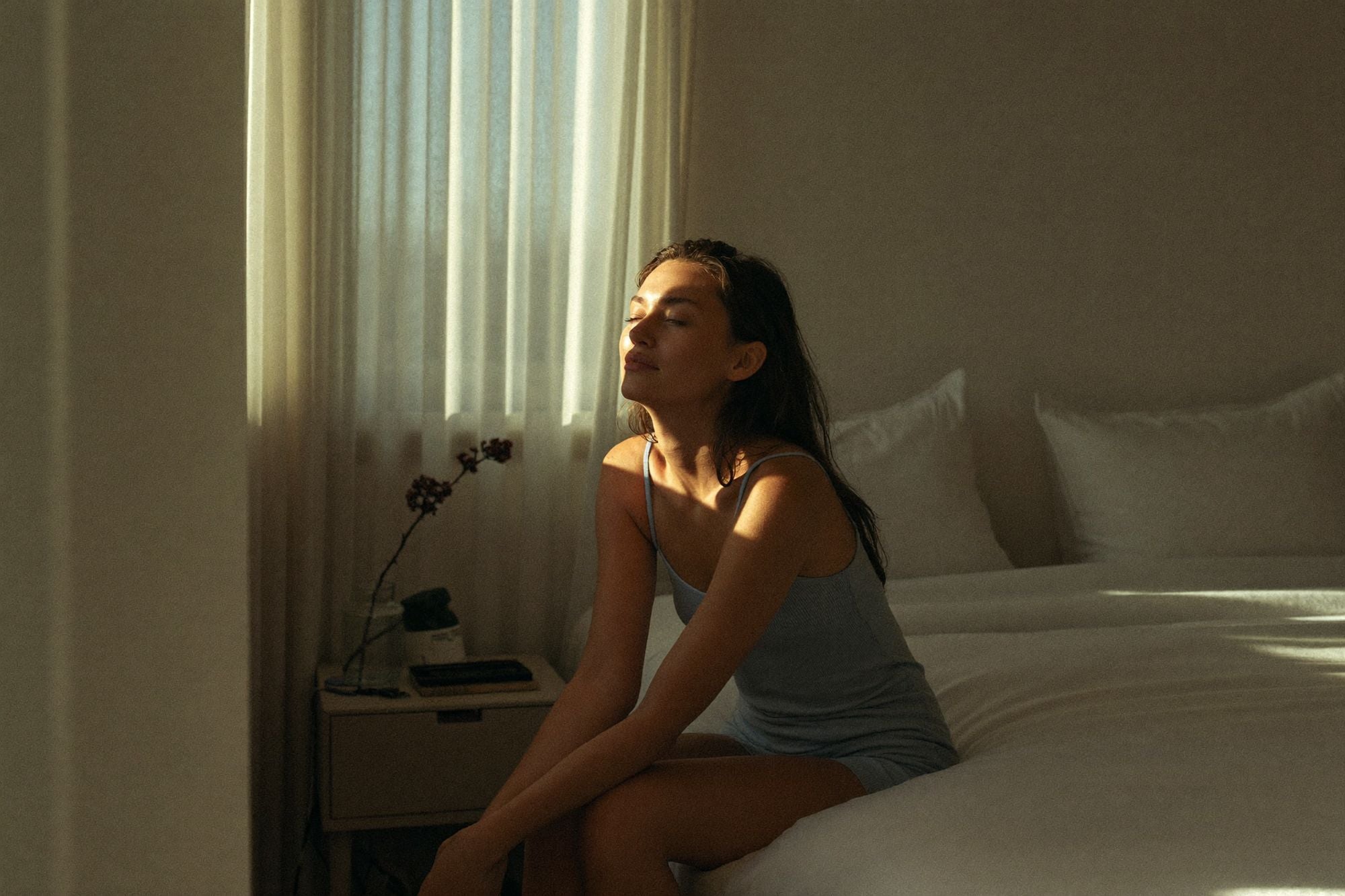 Vrouw zit ’s ochtends op de rand van haar bed